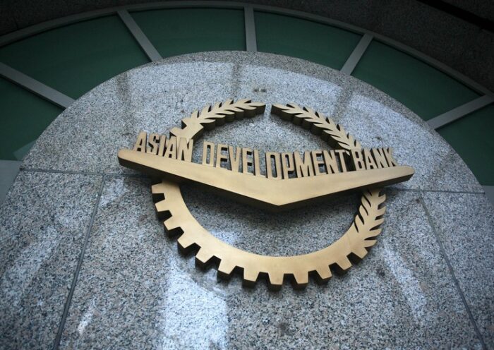 "Asiya İnkişaf Bankının loqosu daş üzərində — qızılı rəngli dişli dairə və dəfnə yarpaqları ilə bəzədilmiş emblem, ortasında 'ASIAN DEVELOPMENT BANK