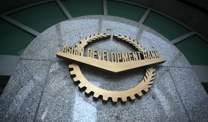 "Asiya İnkişaf Bankının loqosu daş üzərində — qızılı rəngli dişli dairə və dəfnə yarpaqları ilə bəzədilmiş emblem, ortasında 'ASIAN DEVELOPMENT BANK